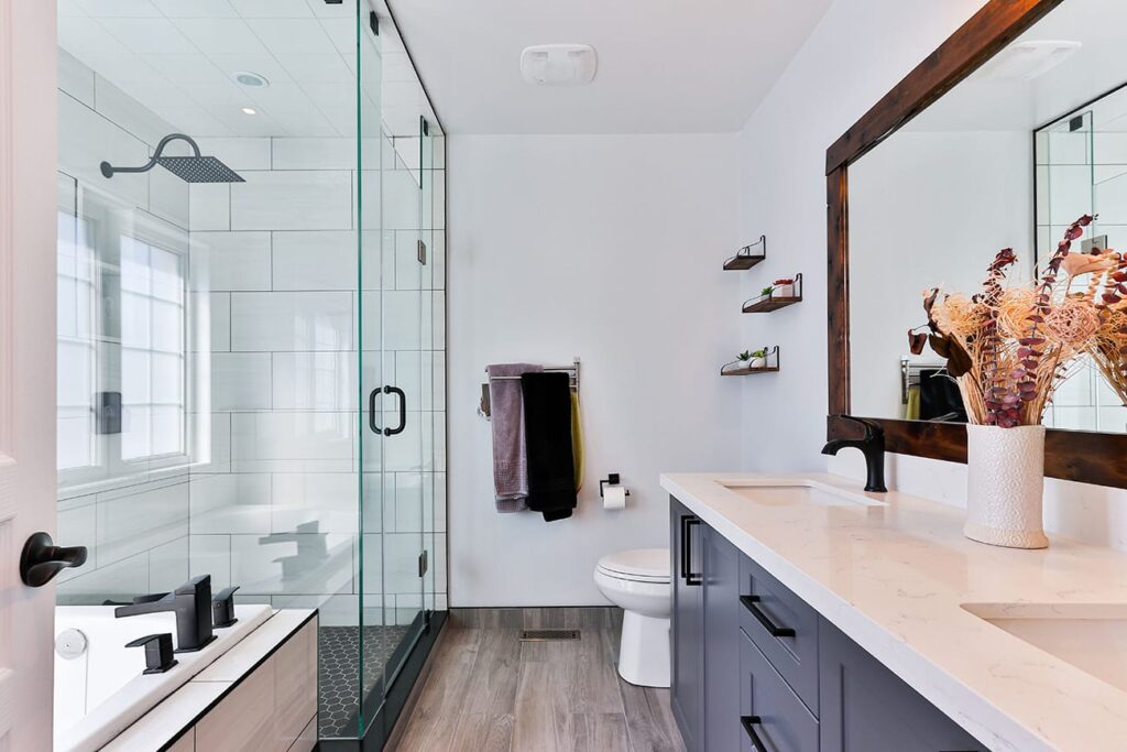 Modern bathroom with a glass-enclosed shower, white subway tiles, and a dark cabinets vanity next to a white tub.